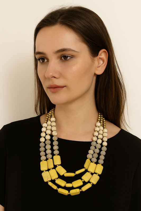 Elegant three-strand statement necklace featuring cream beads, frosted glass elements, and bold yellow rectangular stones, accented with golden spacer beads